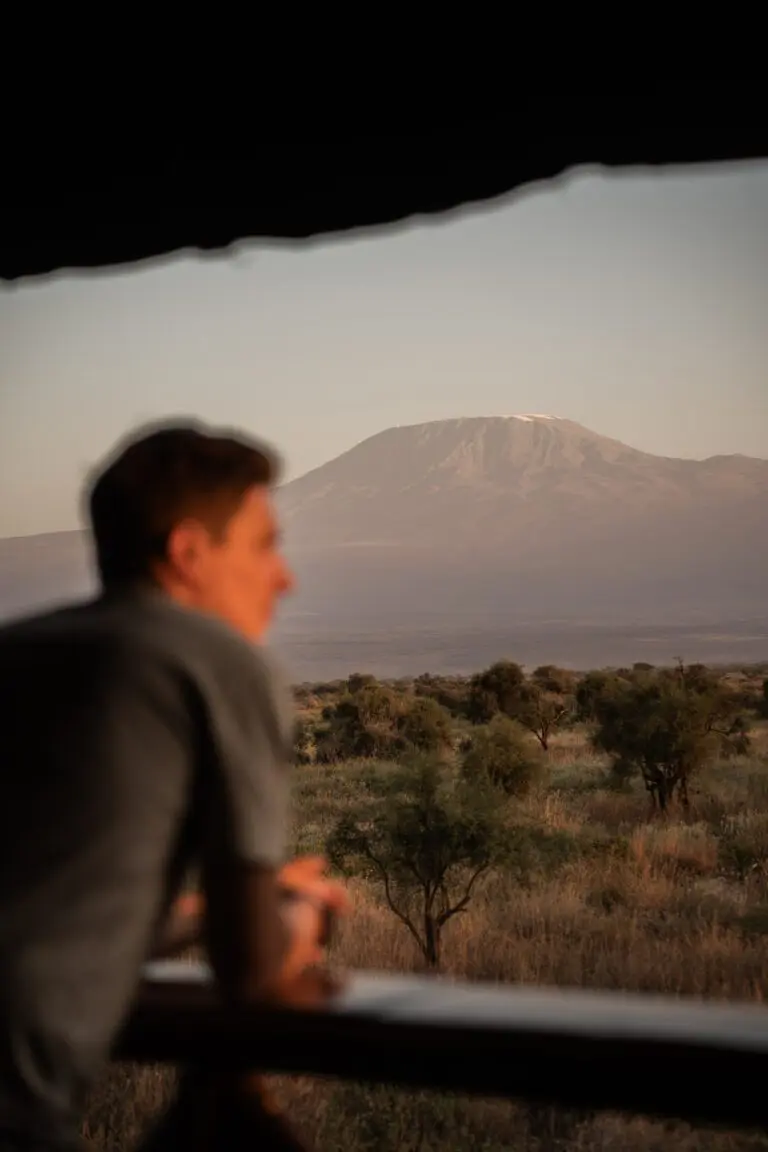 man looking at Mount Kilimanjaro from a safari lodge balcony