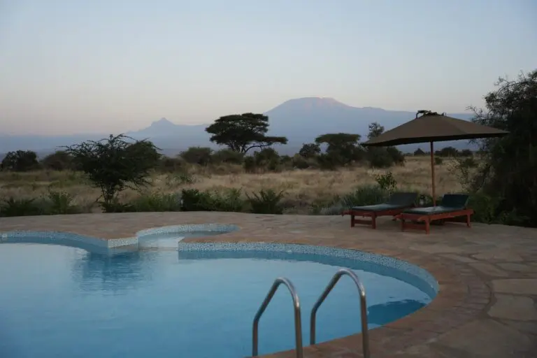 swimming pool with sun loungers and umbrella overlooking mount kilimanjaro
